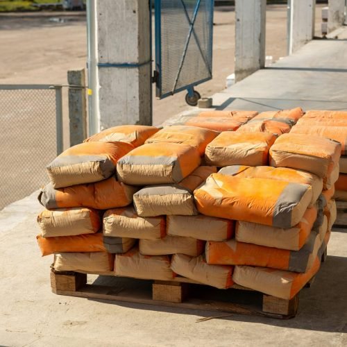 Pile of orange cement bags on a wooden pallet in an industrial setting.